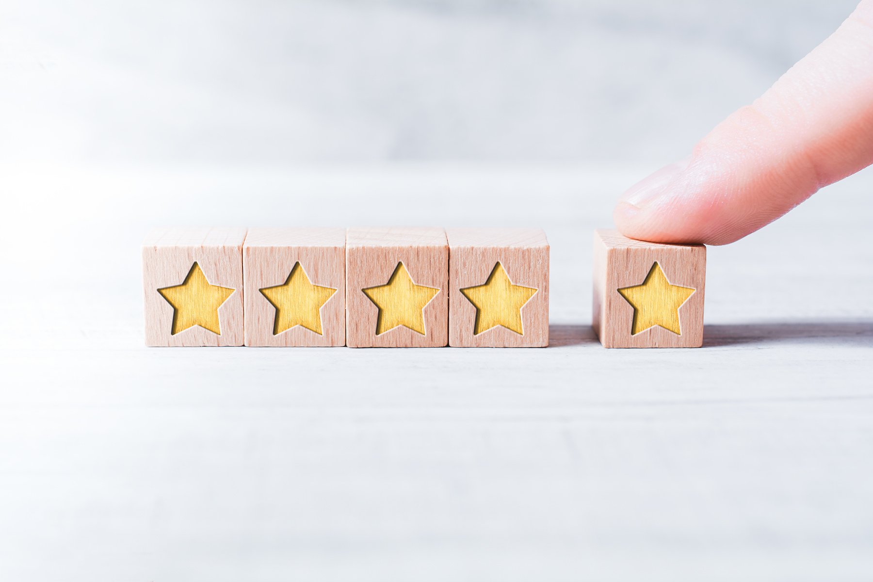 5 Star Ranking Formed By Wooden Blocks And Arranged By A Male Finger On A White Table